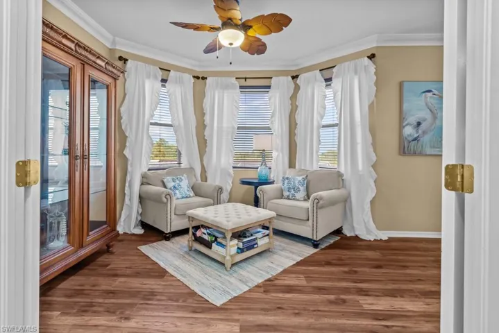 Master Bedroom sitting room features wood-style flooring, a decorative ceiling fan, and multiple windows with blinds and curtains
