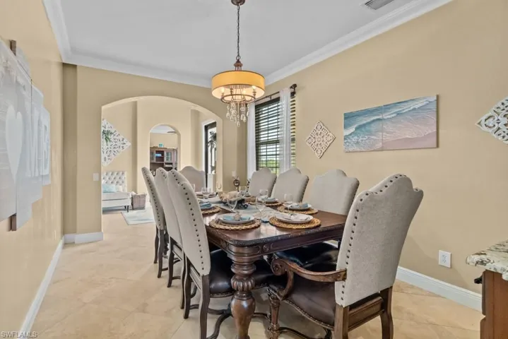 The dining area features elegant crown molding, tile flooring, and an arched doorway