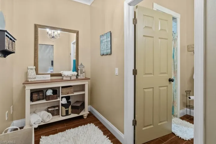 The property features a vanity area with a large mirror, a shelving unit, and warm toned walls