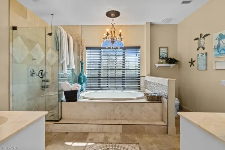 The bathroom features a built-in tub with surrounding tile, a glass-enclosed shower with tiled walls, and a window with blinds