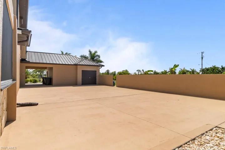 The property features an extensive paved area and a covered carport with a metal roof