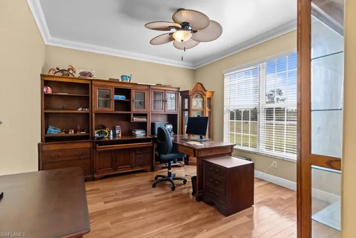 This room features hardwood flooring, crown molding, and a ceiling fan