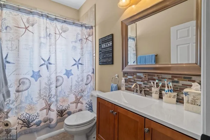 This bathroom features a vanity with a white countertop and a mirror with a decorative frame