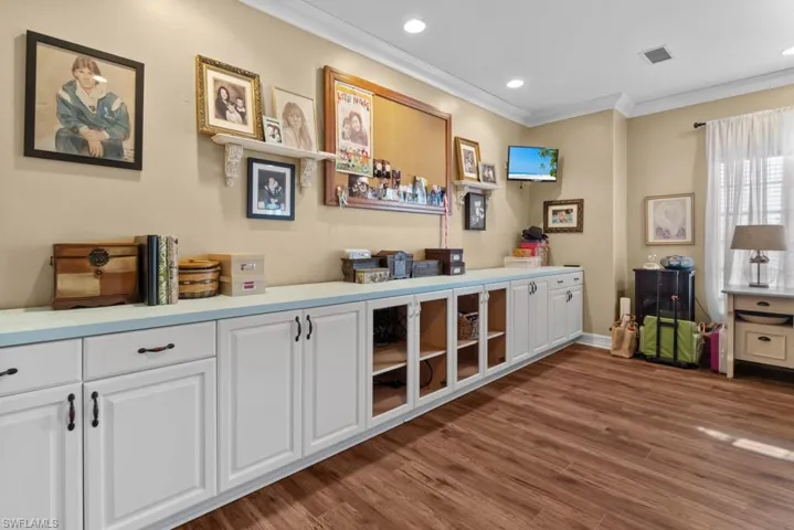 This versatile room features extensive built-in cabinetry with both closed storage and open shelving, complemented by rich wood-look flooring