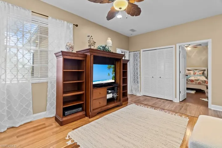 This room features hardwood flooring, light-colored walls, and a ceiling fan with leaf-shaped blades