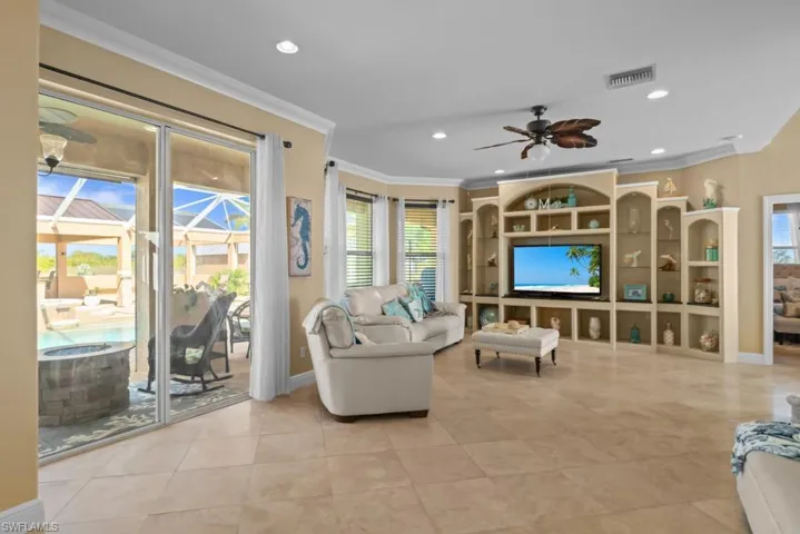 Living room featuring tiled flooring, a ceiling fan, and built-in shelving with an entertainment center