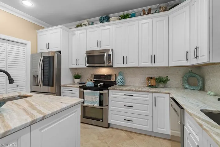 The kitchen features white cabinetry, stainless steel appliances, and light-colored countertops