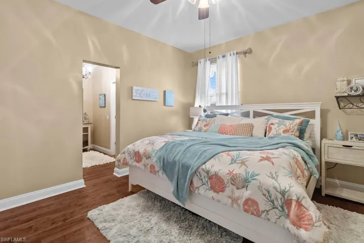 The room features hardwood floors, a ceiling fan, and a window with white blinds