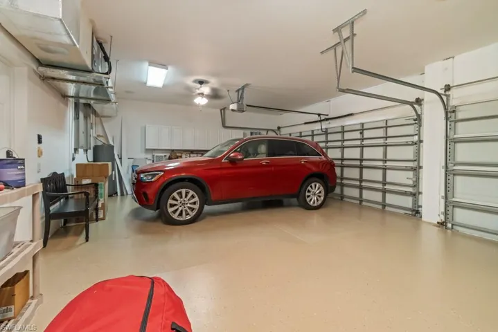 Spacious garage with light-colored flooring, overhead lighting, and two garage doors