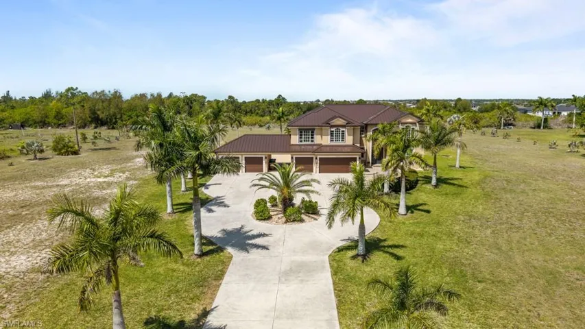The property features a stately exterior with a brown tile roof, a light-colored facade, and a multi-car garage
