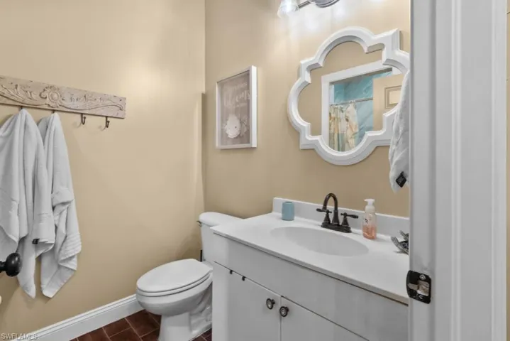 Bathroom featuring a white vanity with a single sink, an ornate white framed mirror, and a toilet