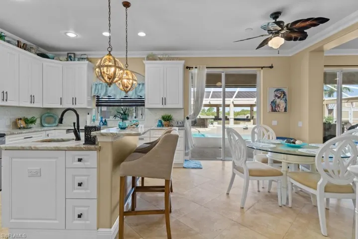 The kitchen features white cabinetry, recessed lighting, and a kitchen island with a built-in sink and a breakfast bar