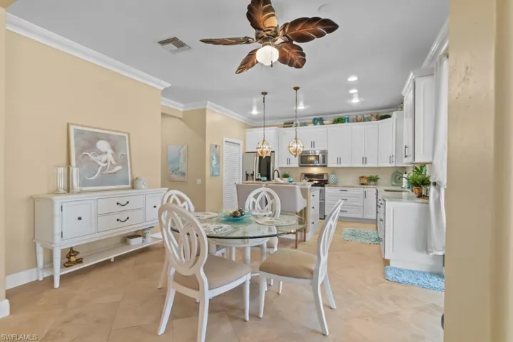 This open-concept area features a kitchen with white cabinetry and stainless steel appliances, and a dining space with a glass-top table