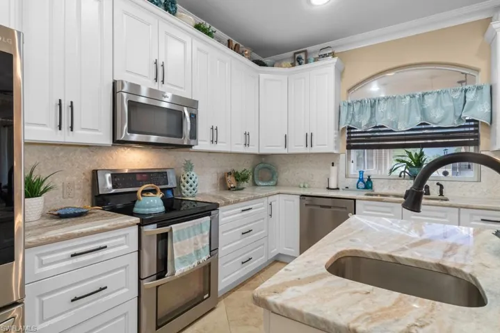 The kitchen features white cabinetry, stainless steel appliances, and light-toned countertops