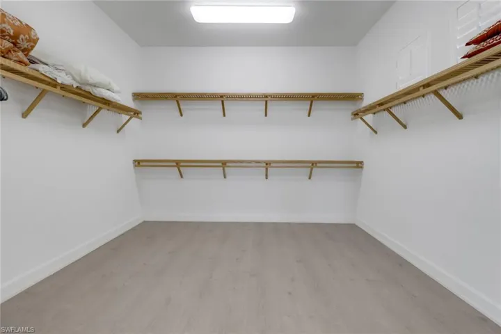 Walk in closet with light hardwood / wood-style flooring