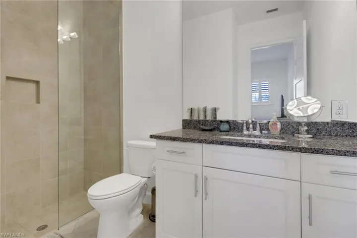 Bathroom featuring toilet, vanity, a tile shower, and tile patterned floors