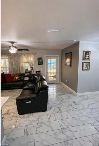 Living room featuring ceiling fan and light marble finish flooring