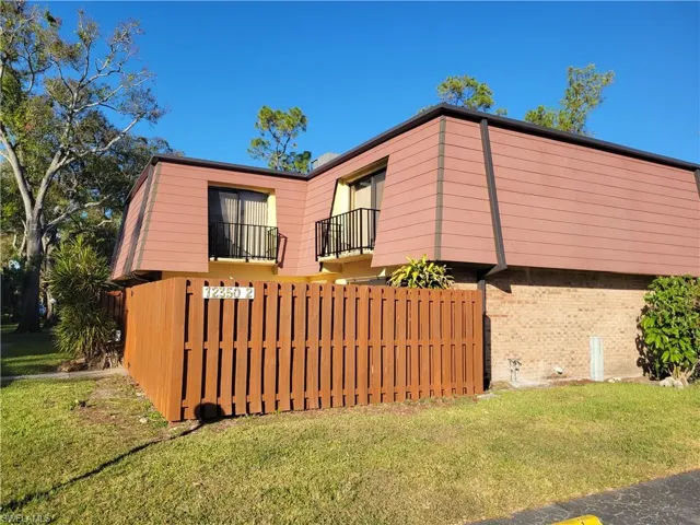 View of property exterior with a yard and a balcony