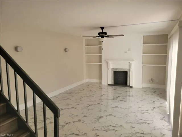 Unfurnished living room with a high end fireplace, built in features, and ceiling fan