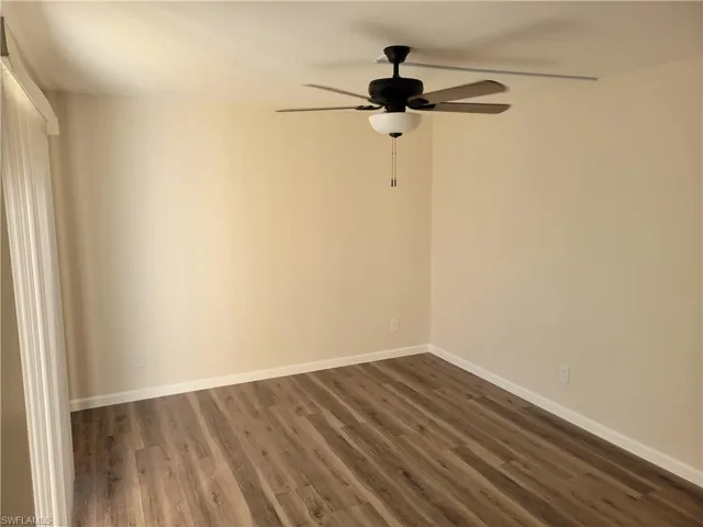 Empty room featuring ceiling fan and dark hardwood / wood-style flooring