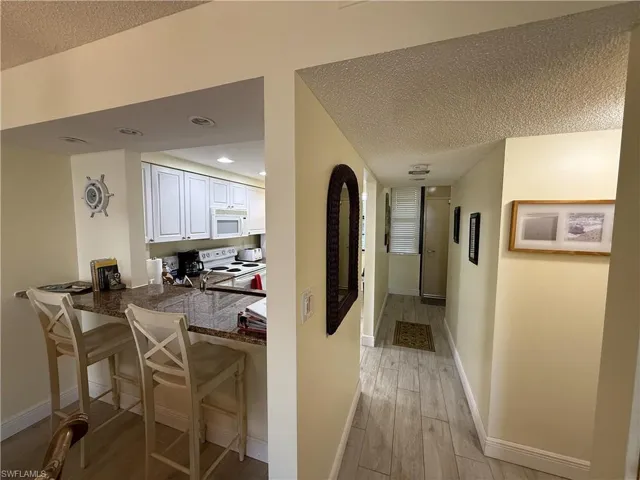 Corridor featuring a textured ceiling, light wood-type flooring, and recessed lighting