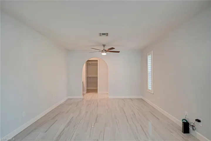 Spare room with light wood-style floors, arched walkways, and a ceiling fan