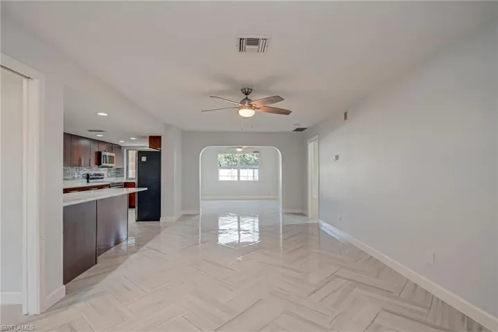 Unfurnished living room with arched walkways, recessed lighting, and a ceiling fan