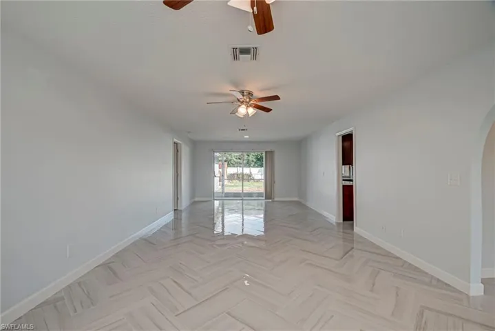 Unfurnished room featuring arched walkways and a ceiling fan