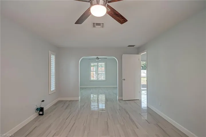 Spare room featuring arched walkways, ceiling fan, and wood finish floors