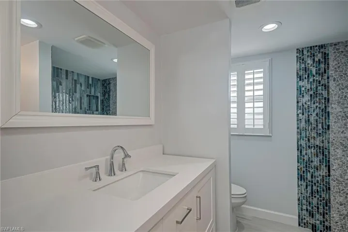 Bathroom with vanity, a shower with shower curtain, and recessed lighting
