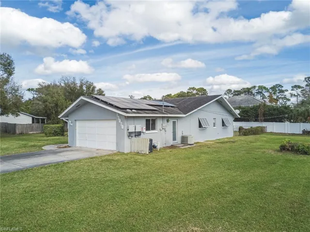 Ranch-style home with concrete driveway, roof mounted solar panels, stucco siding, and an attached garage