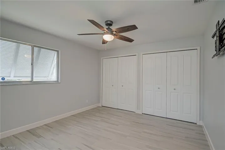 Unfurnished bedroom featuring two closets, ceiling fan, and light wood finished floors