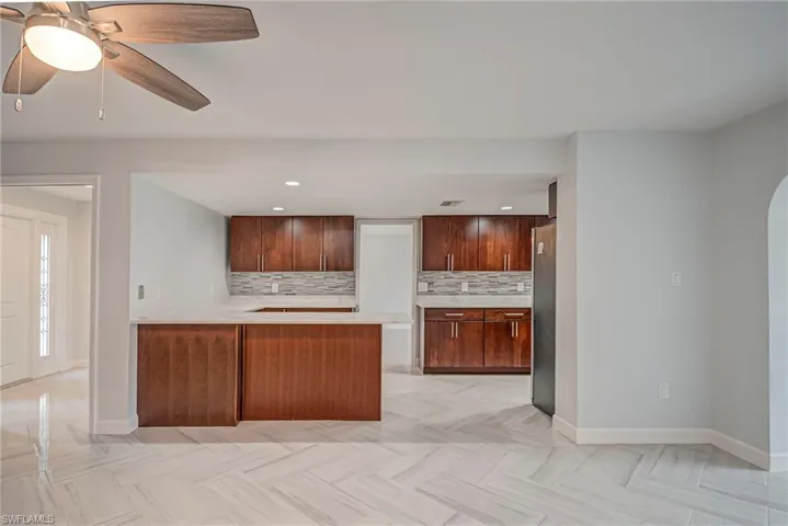 Kitchen featuring a peninsula, tasteful backsplash, freestanding refrigerator, recessed lighting, and a ceiling fan