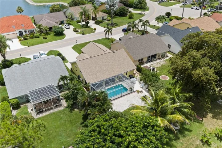 Aerial perspective showcasing a property with a screened-in pool and surrounding patio space