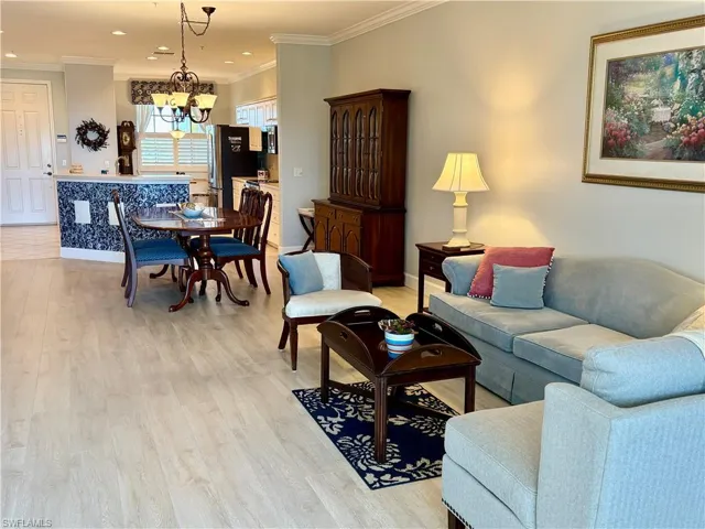 Living area featuring crown molding, light wood-style flooring, and suspended lighting