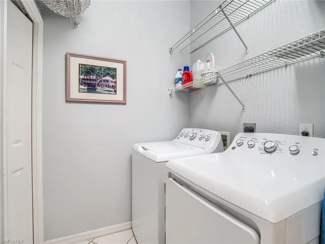 Laundry room with washing machine and clothes dryer and light tile patterned floors