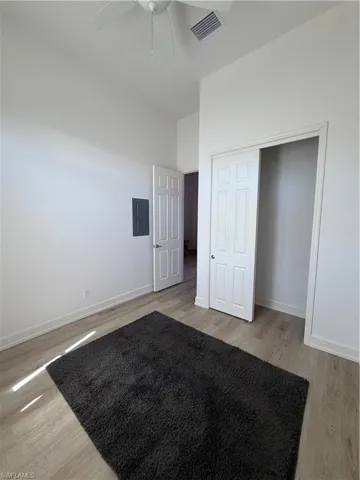 Unfurnished bedroom featuring light wood finished floors, ceiling fan, electric panel, and a closet