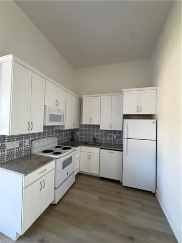 Kitchen featuring white appliances, white cabinetry, and tasteful backsplash