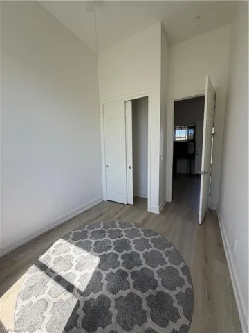 Unfurnished bedroom with light wood-type flooring, a high ceiling, and a closet