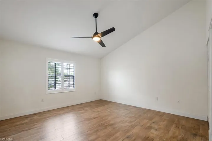 Unfurnished room with vaulted ceiling, hardwood / wood-style floors, and ceiling fan