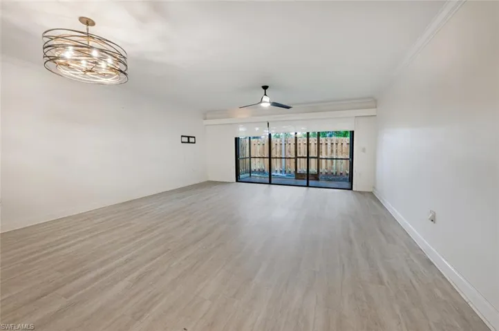 Unfurnished room with ceiling fan with notable chandelier, light hardwood / wood-style floors, and crown molding