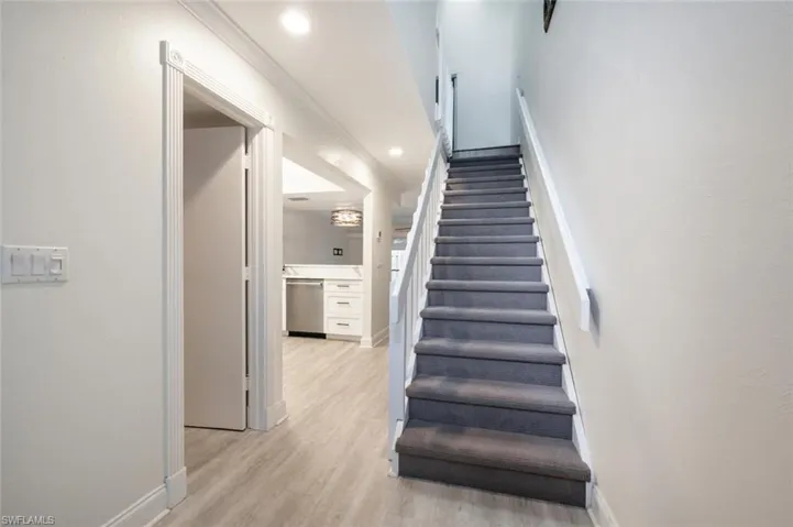 Stairway featuring ornamental molding and wood-type flooring