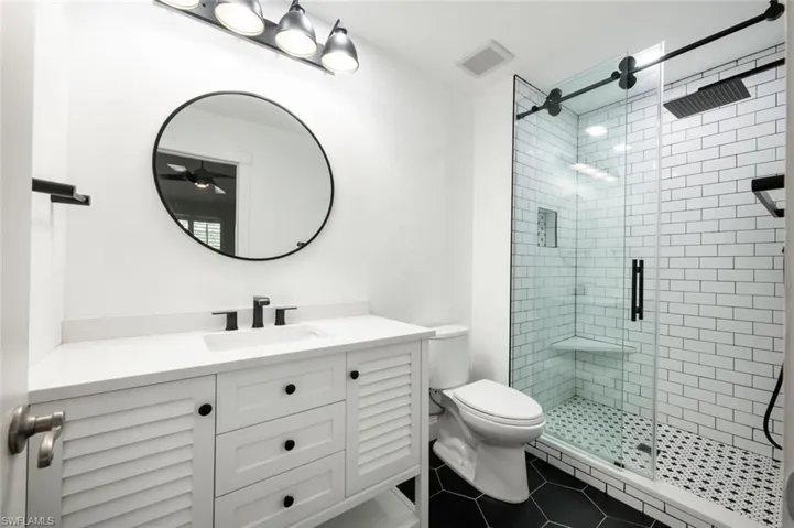 Bathroom featuring tile patterned flooring, vanity, toilet, and walk in shower