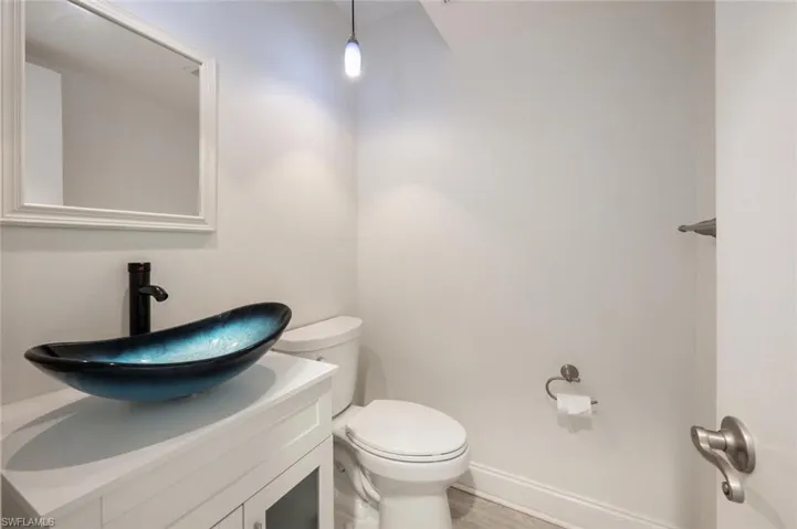 1/2 Bathroom featuring vanity, toilet, and wood-type flooring