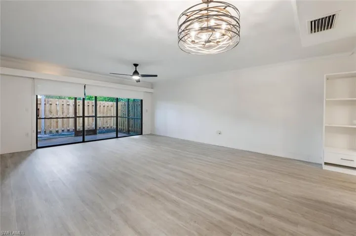 Empty room featuring ceiling fan with notable chandelier, ornamental molding, and wood-type flooring