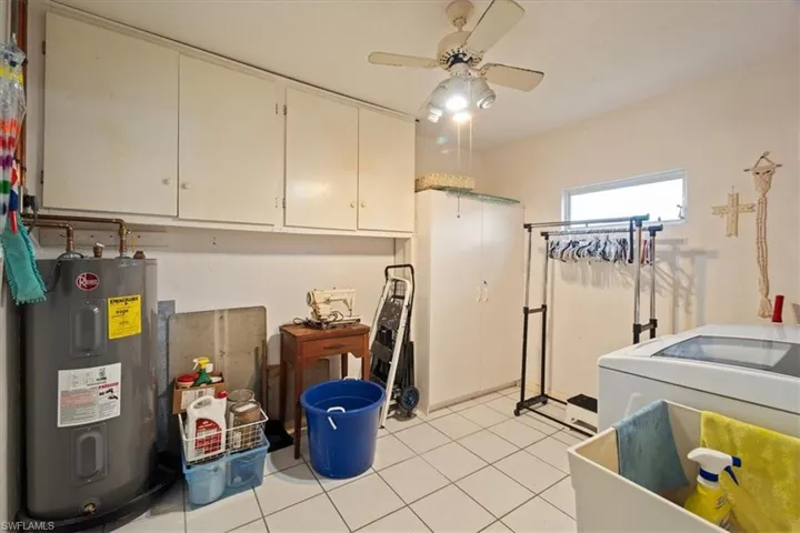 Laundry area with cabinets, electric water heater, ceiling fan, light tile patterned floors, and washer / clothes dryer