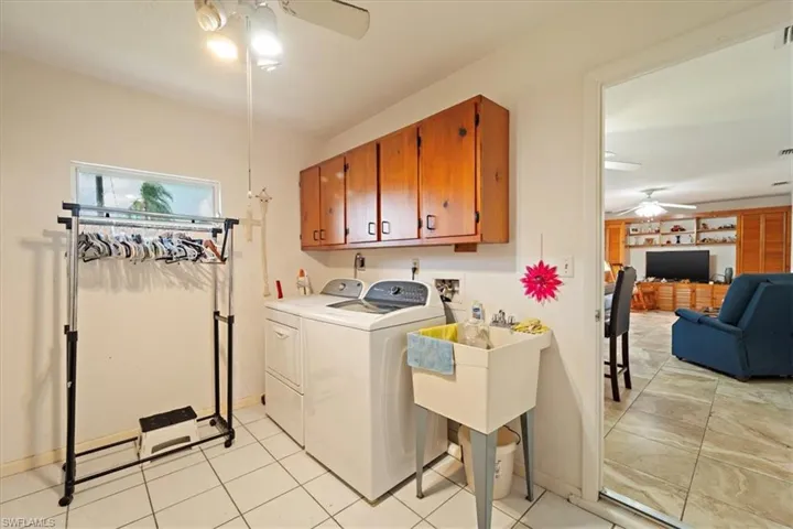 Clothes washing area featuring cabinets, independent washer and dryer, light tile patterned floors, and ceiling fan