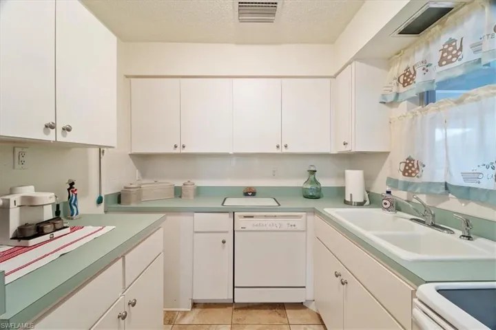 Kitchen with a textured ceiling, sink, dishwasher, range, and white cabinetry