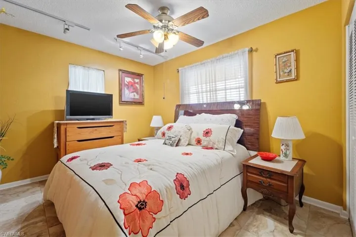 Bedroom with a textured ceiling, ceiling fan, and rail lighting