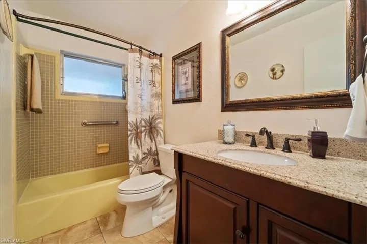 Full bathroom with toilet, vanity, tile patterned floors, and shower / bath combo with shower curtain